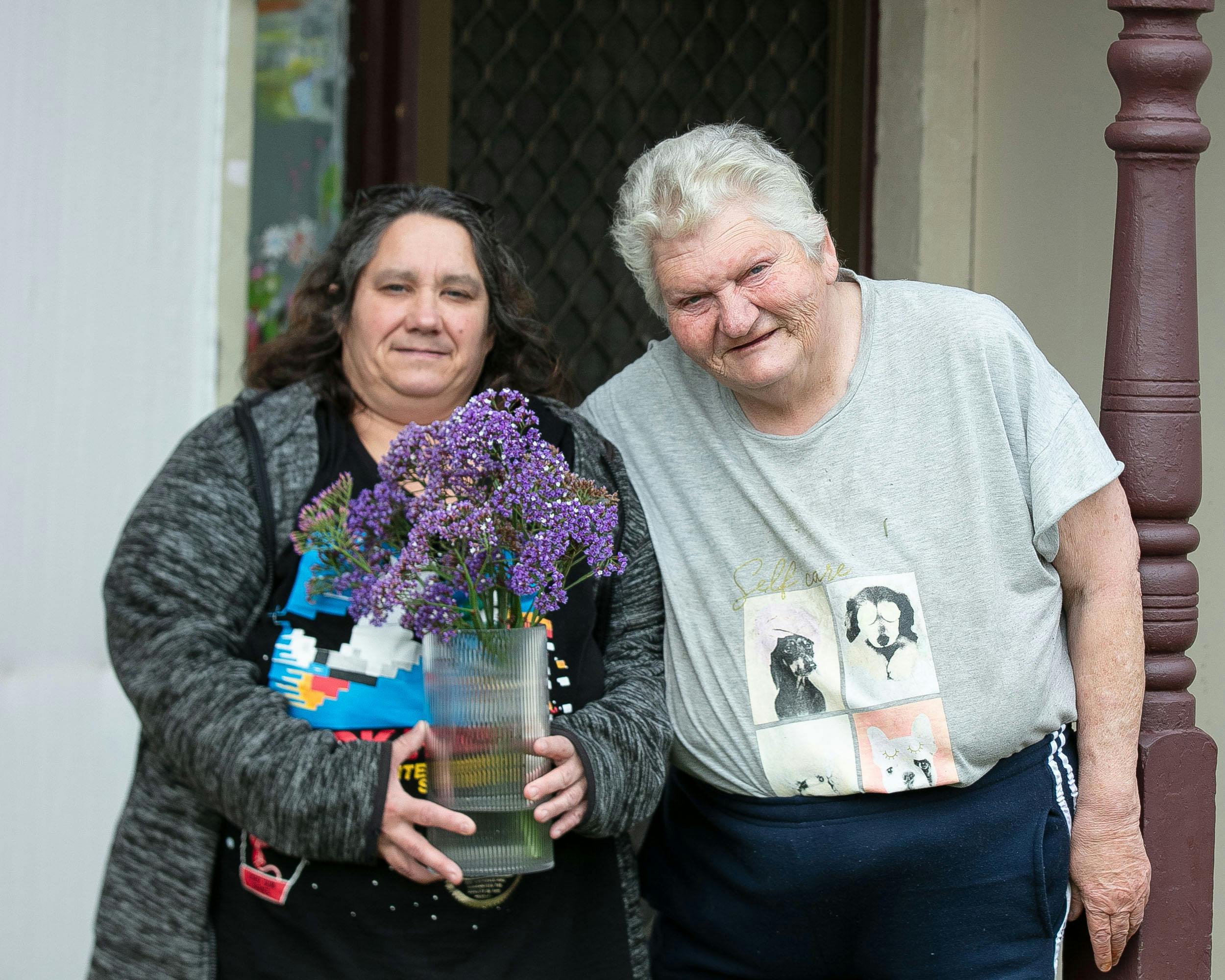 Allcare Support worker and individual smiling with flowers.